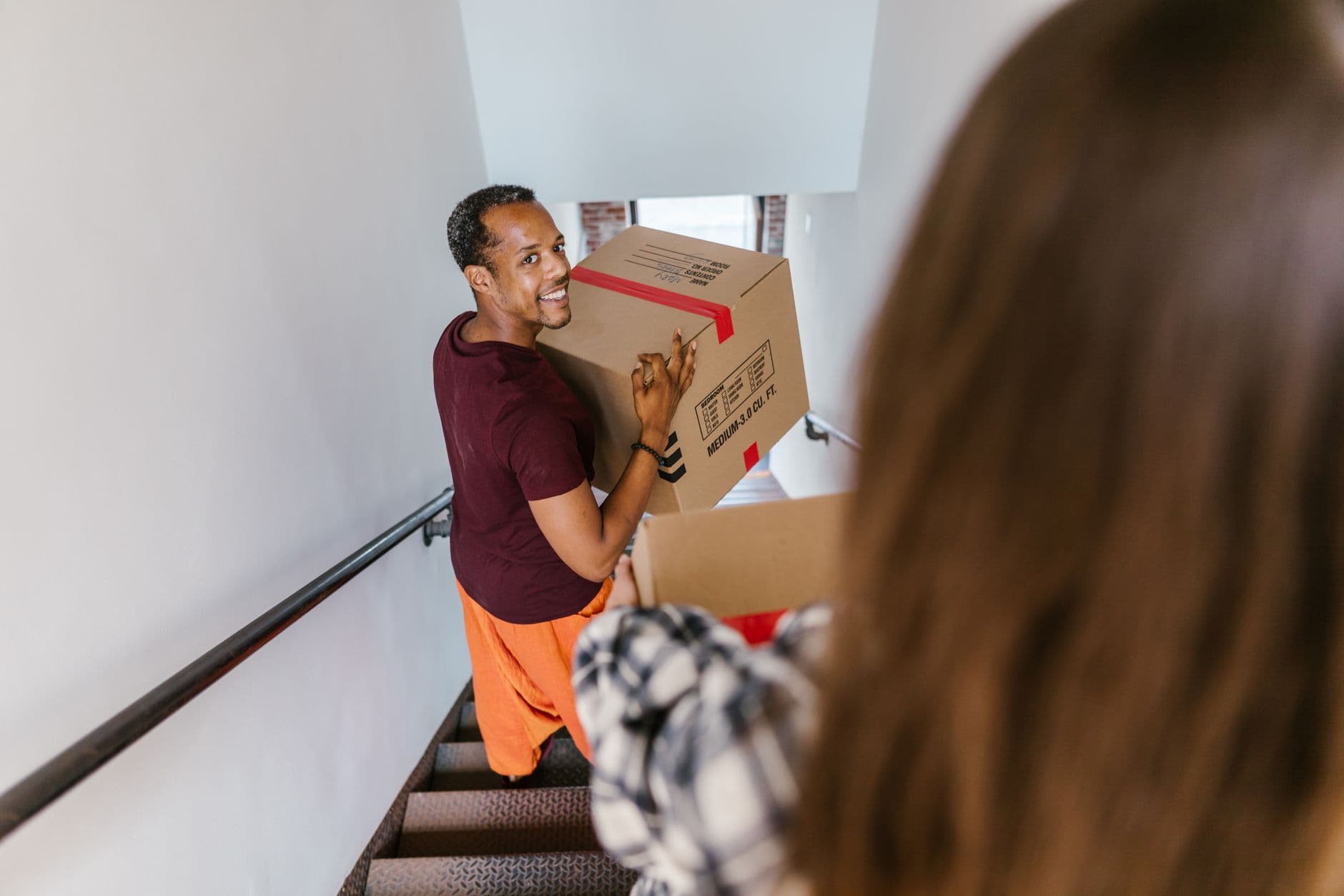 Déménageurs professionnels portant des cartons dans un escalier d'immeuble